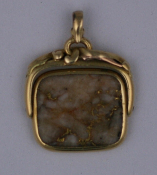 Unusual flip fob with large gold quartz stone from the late 19th Century. Mounted in heavy 14k gold mount with transitional A+C/Art Nouveau applied scroll motifs across the top edge. 
A wonderful relic of the American Gold Rush. Marbleized gold