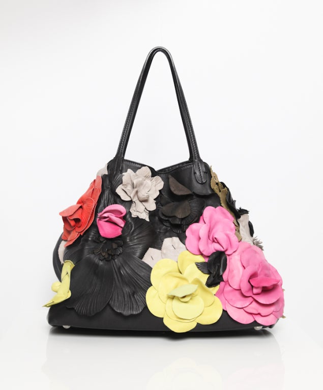 This Valentino Summer flower tote is another femme-fatale bag from the spring collection.
This very nearly lip-shaped tote is decked in supple nappa leather flowers in bright, bold colors which captivate and catch the eye. The unusual color