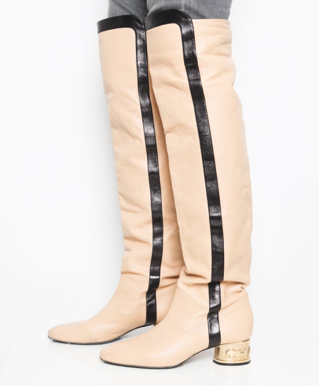 Unique and vintage knee-length boots for all fashionista's who love Chanel. 
Creamy color with black stripes on the sides. Round top and impressive golden, shiny heel with Chanel logo.