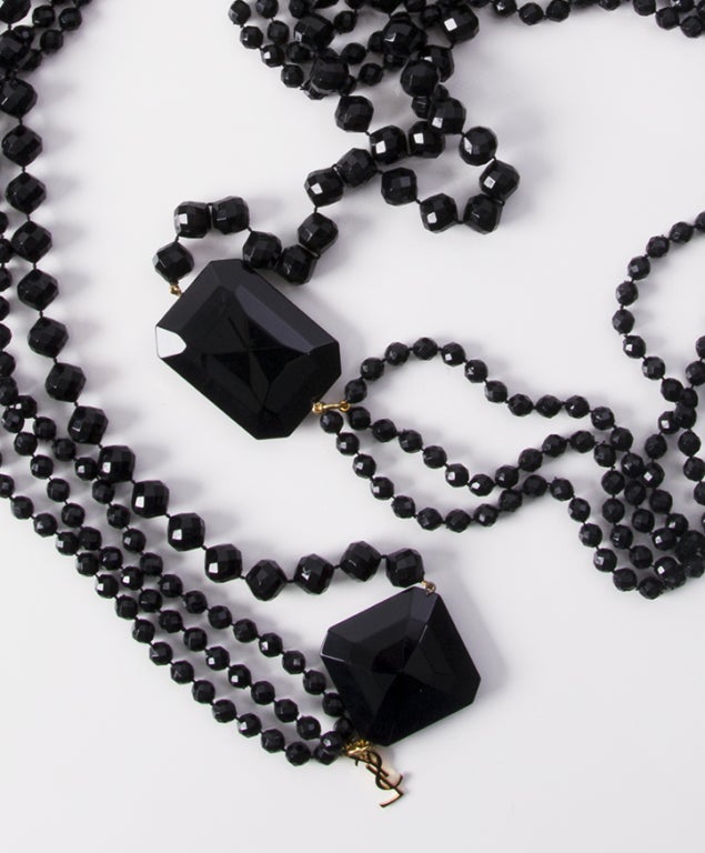 Vintage oversized Yves Saint Laurent necklace made of one and tripple strands of shiny black beads held together by 2 larger square pieces to balance out the form of the necklace when hung around the neck. 

Full length: 145cm