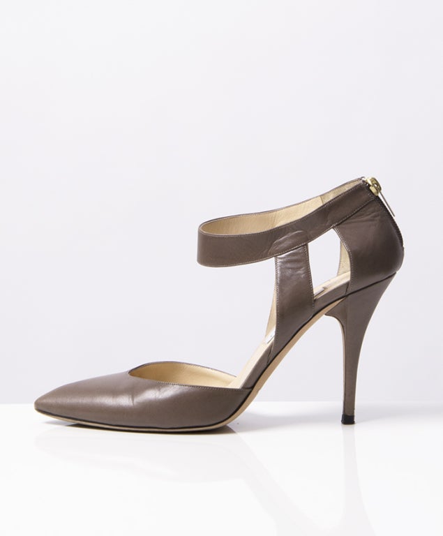 These Jimmy Choo taupe stiletto pumps are a modern take on the classic  Mary Jane pump. The pair features pointed tips and elegant cut outs at the ankles .