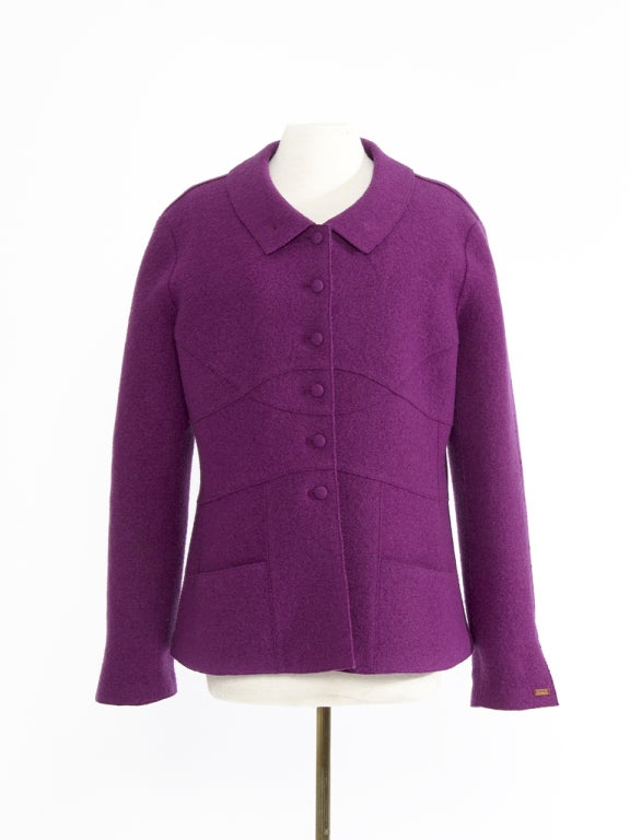 This 100% wool Chanel blazer jacket is made in a beautiful warm violet hue. All features are kept sober with the color being the main eye-catcher of this precious garment. Discrete buttons, a subtle seam line pattern and a feminine rounded neckline