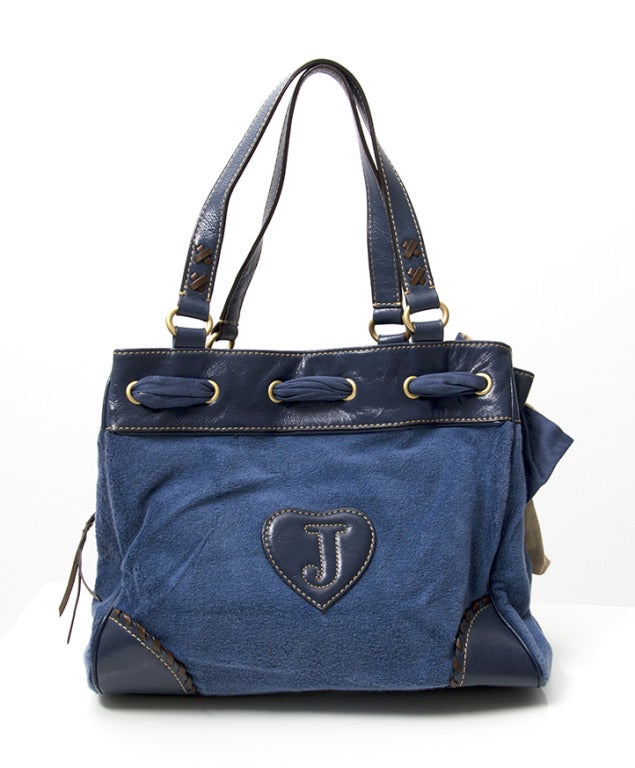 Blue handbag by Juicy Couture. A fun shoulder bag, adorned with playful cotton bow, heart lockit and leather tassle. Comes with a gold leather heart shaped pocket mirror attached to the inside of the bag with a ribbon saying 'I am the fairest'.