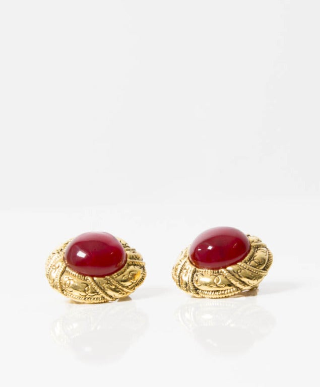 Chanel golden earrings with the CC logo engraved. The earrings have a giproix ruby colored stone.