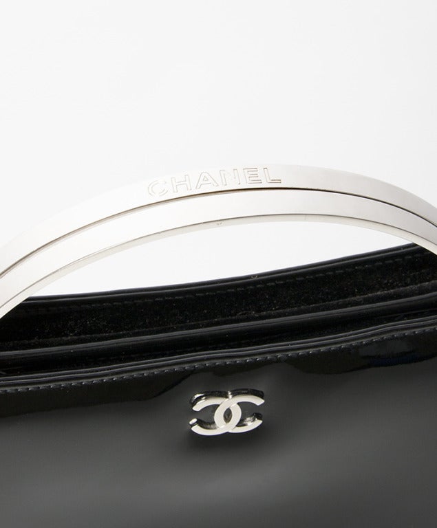 A clutch or evening handbag in patent black leather. Authentic Chanel. Comes with certificate card: 5994086 and original dustbag. 

Chromium hardware throughout. 
Interior lining made from buttery soft calfskin, with 2 zipper pockets and room