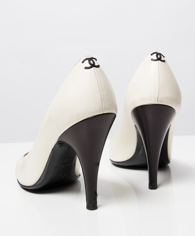 Chanel black and white leather peep toe pump. Black and white leather straps at the toe. Signature CC logo at the back of the shoe. Still in very good condition. From the leather you can see that the pumps have been worn. Some tiny signs of wear.