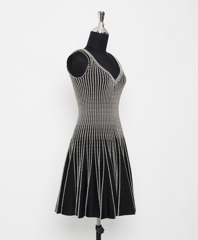 Alaïa black and white striped sleeveless dress. Black and white knitted wool blend dress from Alaïa featuring a V-neck, a white striped embellishment on the body, a fitted waist, a voluminous pleated skirt section and a central zip fastening at the