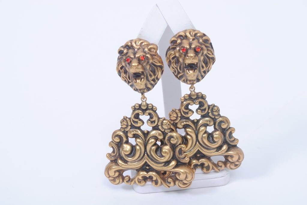 Quintessentially Joseff of Hollywood and with an early hallmark, these large earrings feature a lion head clip-on supporting a triangular-shaped pendant of pierced repoussé C-scrolls, all with the iconic patina of antiqued gold for which the house