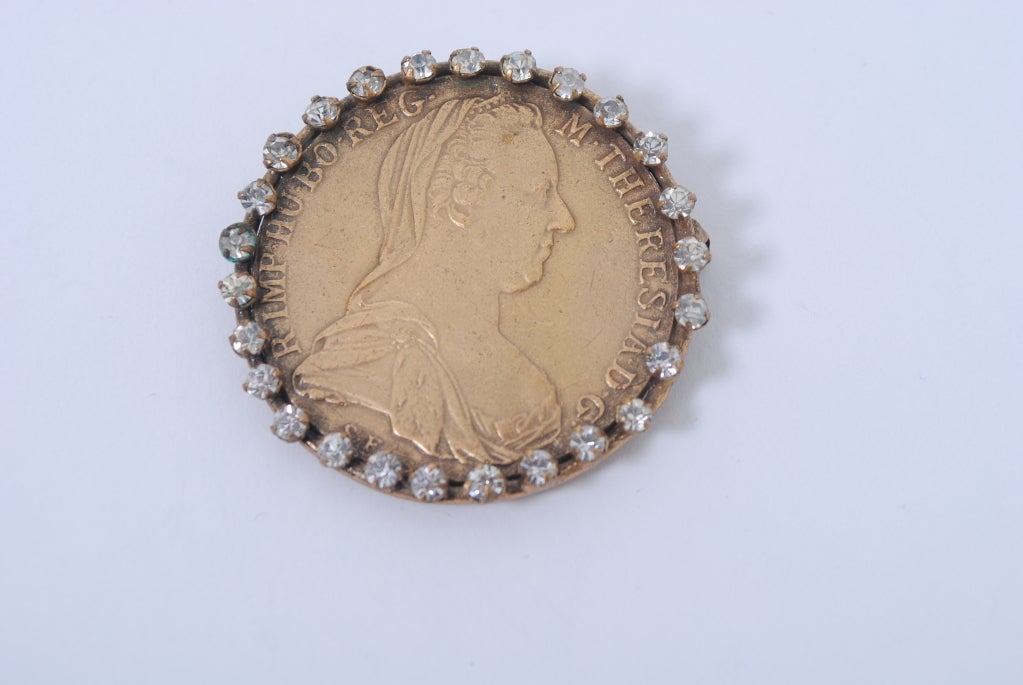 Joseff of Hollywood rare coin brooch, the coin set in a bezel with prong-mounted rhinestones. The coin is a Maria Theresa taler, which began being minted in Austria in 1841 and which has continued in production around the world throughout the 20th