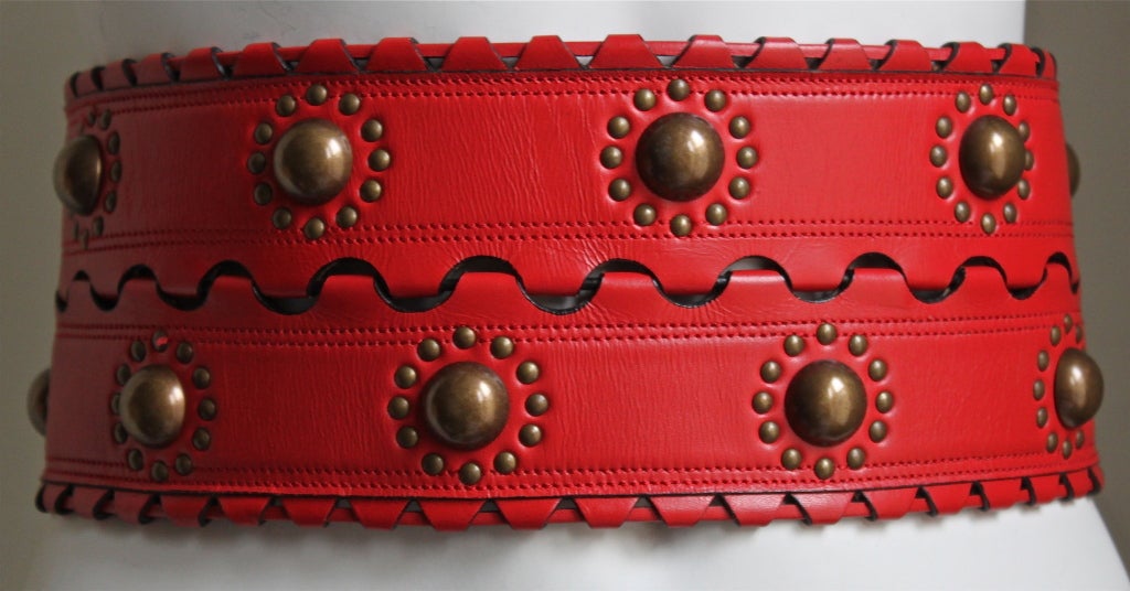 Red leather corset belt with brass studs designed by Azzedine Alaia dating to the late 1993. Labeled a French size 70. Made in France. Excellent condition.