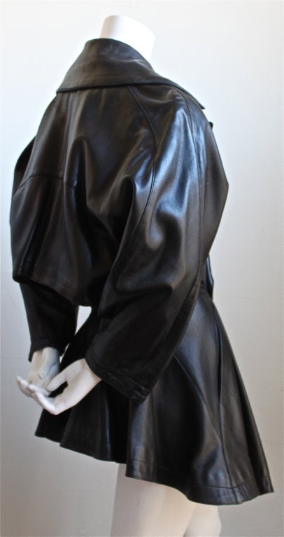 Beautifully seamed jet black leather coat from Azzedine Alaia dating to winter of 1985/1986. Very flattering fit. Bottom flares at waist and hemline dips in the front. Very interesting back vent. Phenomenal construction. Fits a US size 4-6. Made in