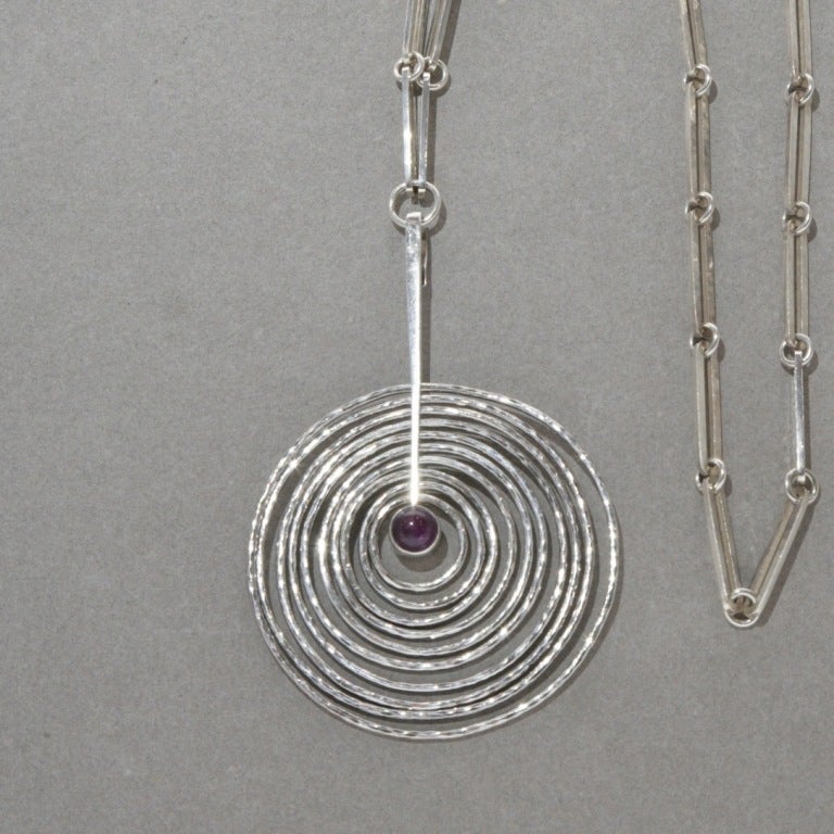 Hand-hammered concentric circles dangle around an amethyst center to create a visually stunning effect. Includes featured chain, no. 195A, 25 inches. Alternate option neck ring, 174, 5.5 inches x 6 inches.