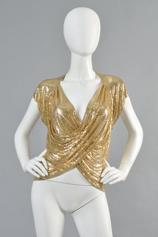 Killer 1970s Ferrara for Whiting & Davis gold chain mail top. Incredible piece! Heavyweight metallic gold metal features a plunging neckline and cross-over draped bodice. Metallic gold leather trimmed neckline with draped sleeves. Hidden side zipper.