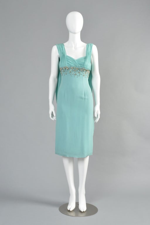 Beautiful 1960s seafoam blue silk cocktail dress. Grecian-style gathered bust with beaded floral details. Draped scarf back.

MEASUREMENTS
Bust: 33