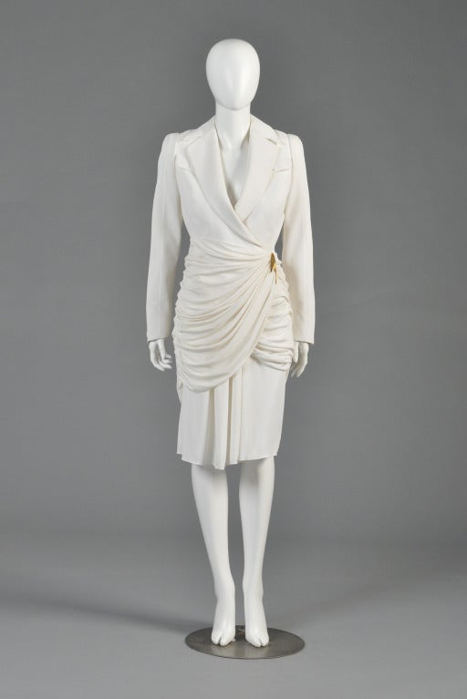 Spectacular 1980s Thierry Mugler all white architectural suit. Fitted jacket with plunging neckline + super draped asymmetrical jersey hem. Massive gold metal boomerang buckle. High-waisted draped skirt. Excellent vintage condition - freshly cleaned