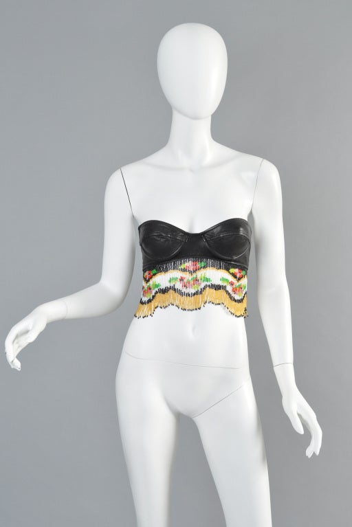 Incredible vintage 1989 Moschino bustier crop top. Black buttery soft calfskin with scalloped beaded fringe. Incredible beaded floral pattern among chevron stripes. Truly a rare + unique piece. Size XS + best fits B-C cup.