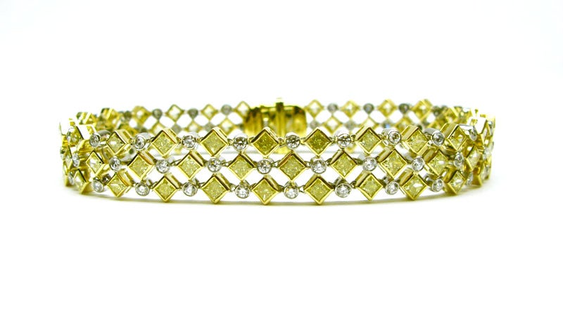 This bracelet is perfect for someone who loves a unique piece that makes a statement! This one of a kind bracelet is crafted in 18K yellow gold and platinum, and features three rows of alternating fancy yellow princess cut diamonds, and round white