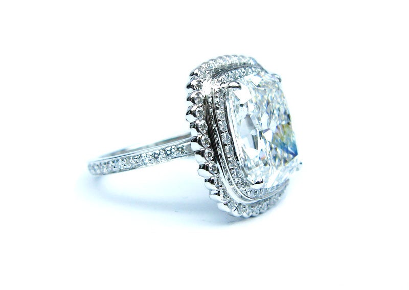 Exquisite 6.01ct G color SI1 clarity GIA certified cushion brilliant diamond with a handmade platinum mounting. This gorgeous ring contains 0.68ctw of both pave and bezel set diamonds that form a frame around the center stone.