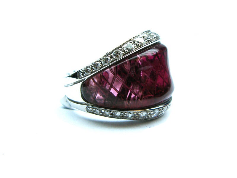Whimsical Ambrosi signed 18kt white gold ring with a center rubellite tourmaline and a border of 46 round brilliant diamonds weighing approximately 3.20ctw. The crisscross pattern in the gallery creates a unique design within the stone.