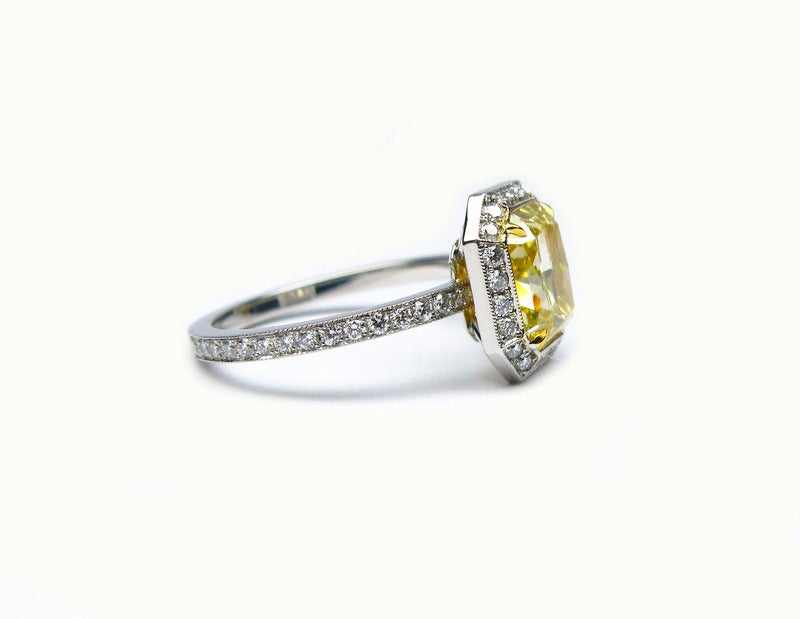 This gorgeous platinum and 18kt yellow gold ring features a 2.29ct GIA certified fancy yellow radiant cut diamond with VS2 clarity. The yellow diamond is surrounded by a pave diamond frame totaling  0.52ctw. This ring is undeniably beautiful and