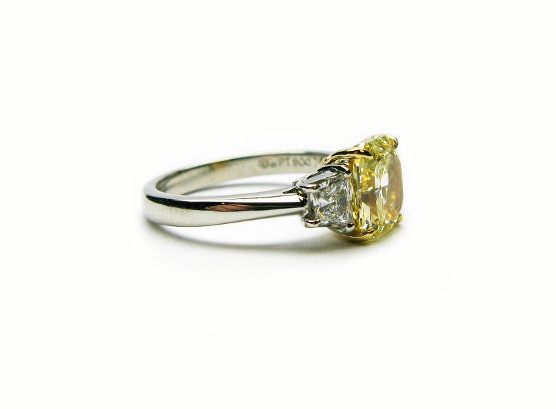 This beautiful platinum and 18kt yellow gold ring features a 2.01ct GIA certified fancy yellow radiant cut diamond with VS2 clarity. The yellow diamond is set between two diamond traps totaling 0.57ctw. This ring is a stunning piece that is sure to