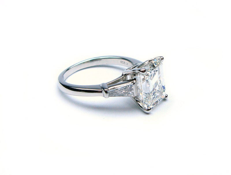 This gorgeous GIA certified 3.32ct H color VS1 clarity emerald cut diamond is set in a platinum ring in between 0.50ctw of tapered diamond baguettes. This ring's classic charm will never go out of style.