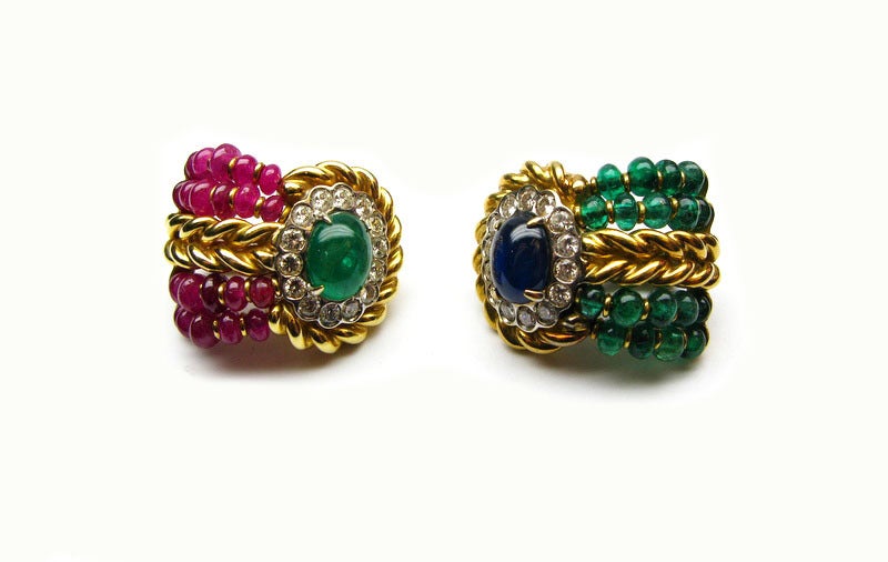 These Giovane signed braided 18kt yellow gold earrings feature ruby and emerald beads, emerald and sapphire cabochons, and bezel set round brilliant diamonds. These unique earrings are the perfect accessory for the fashion forward woman with