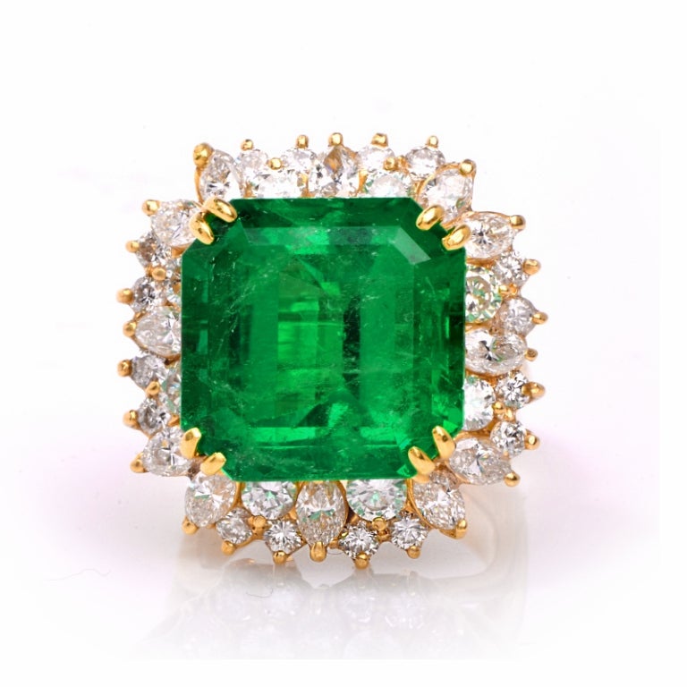 This impressive emerald and diamond cocktail ring will add glitz and glamour instantly! Finely crafted in solid 18K yellow gold, this ring is set with 1 genuine natural Colombian emerald approx. 20.00 ct, prong set. The gorgeous green emerald is is