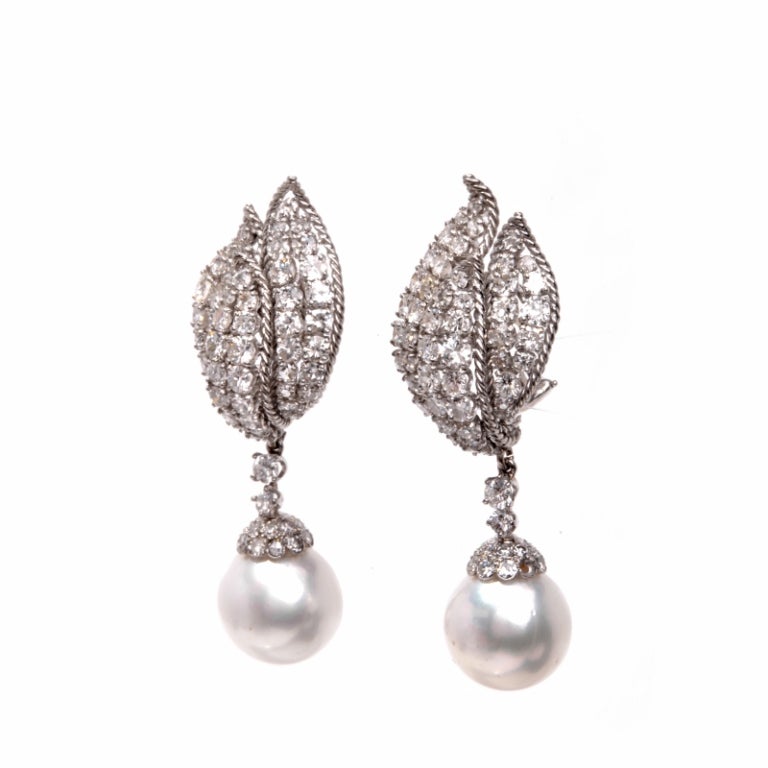 These luxurious estate drop earrings are crafted in solid 18K white gold. These clipback earrings are accented with some 140 genuine round European cut diamonds approx. 11.00cttw, H color, VS clarity, prong set. Also displayed are 2 genuine AAA