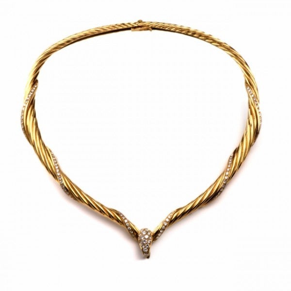 This bold and opulent estate Retro style necklace is crafted in solid 18K yellow gold, weighs approx. 95.0 grams and measures approx. 16 ½ inches around the neck. Designed as a rope style choker necklace, embellished with diamond-swathed scrolls and