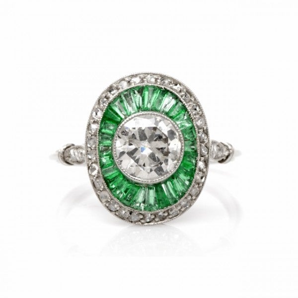 This estate diamond and emerald engagement ring is crafted in solid platinum, weighing approx. 4.7 grams. Designed as a breath-taking oval plaque measuring approx. 20mm x 14mm, this alluring engagement ring exposes a significant genuine 1.12ct