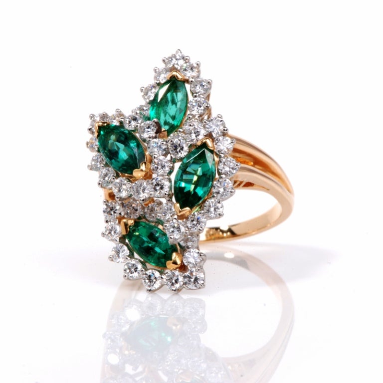 This stunning original Oscar Heyman cluster ring is crafted in solid 18K yellow gold and platinum. This ring is accented with 4 genuine marquise cut very fine emerald  approx. 5.00 ct . They are framed  by some 43 genuine round cut diamonds approx