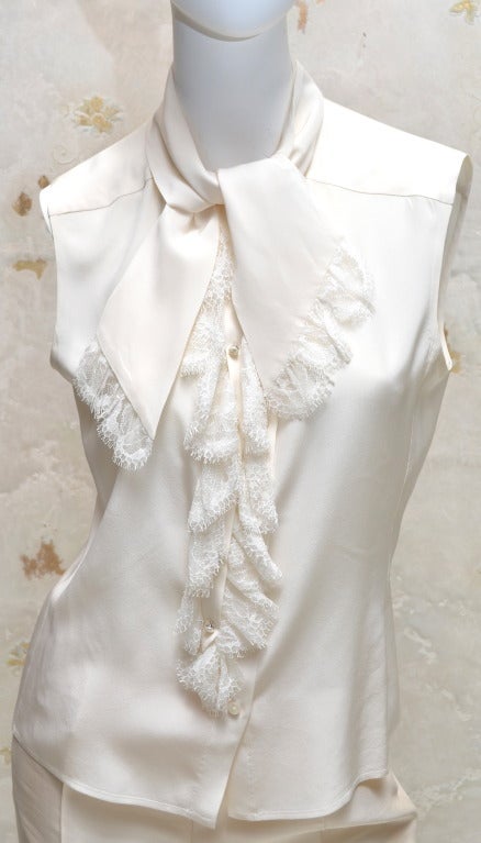Chanel Tuxedo jacket from 2004 size 42. Chanel black velvet jacket with satin collar and piping. Cream lace button in sleeve cuff pieces. Cream silk sleeveless blouse with lace down front and lace trimmed tie neck. Pearl CC buttons on blouse. Black
