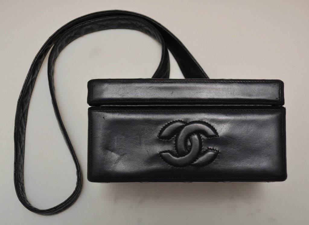 Chanel Black Vintage leather Quilted Box Handbag featuring a CC embossed on the bottom, Quilted gold hardware, and a flat leather shoulder strap.

Measurements:
7” x 3.5” x 5.5”