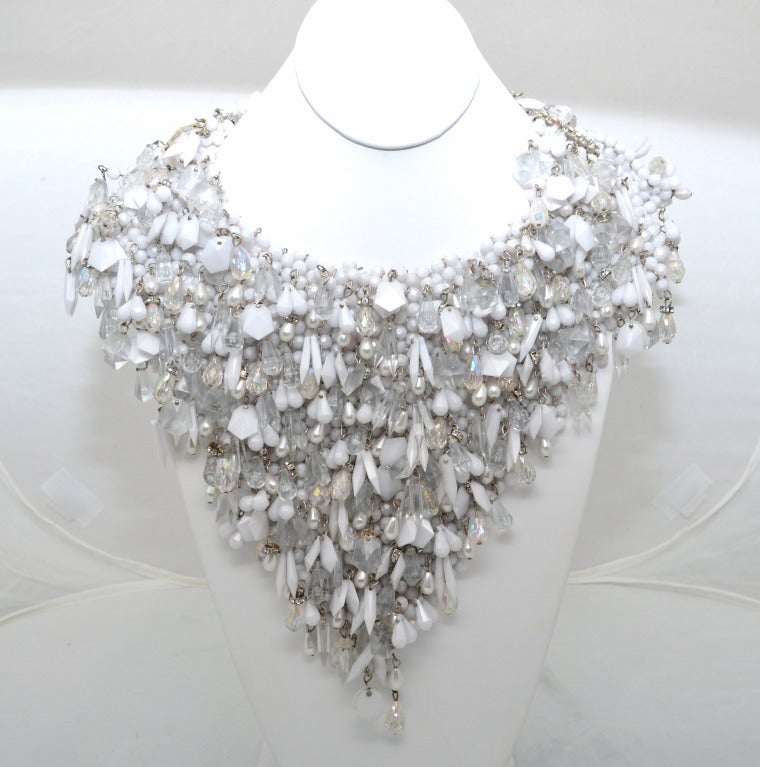 Massive 1960's beaded collar with plastic beads, several clear shaped plastic and glass beads, rondelles, rhinestones and teardrop pearls all held together with silver o rings. Rhinestone clasps at each shoulder are 2 inches wide. Impressive quality