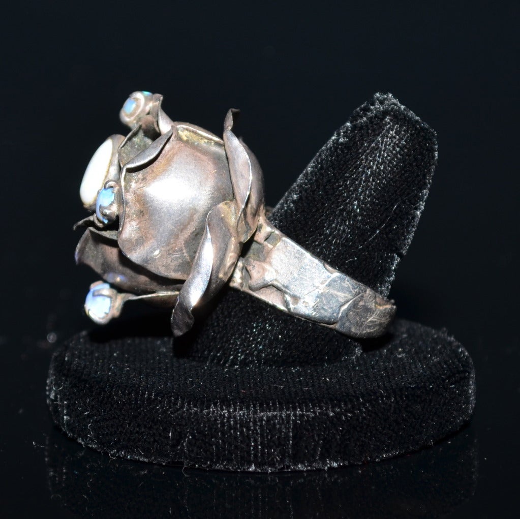 Rachel Gera Modernist sterling rose ring with white opal center stone and 3 smaller bluish stones. From Israel, C.1970. Signed on underside Gera 925 Israel. 

Rose on ring measures approximately 1 1/2