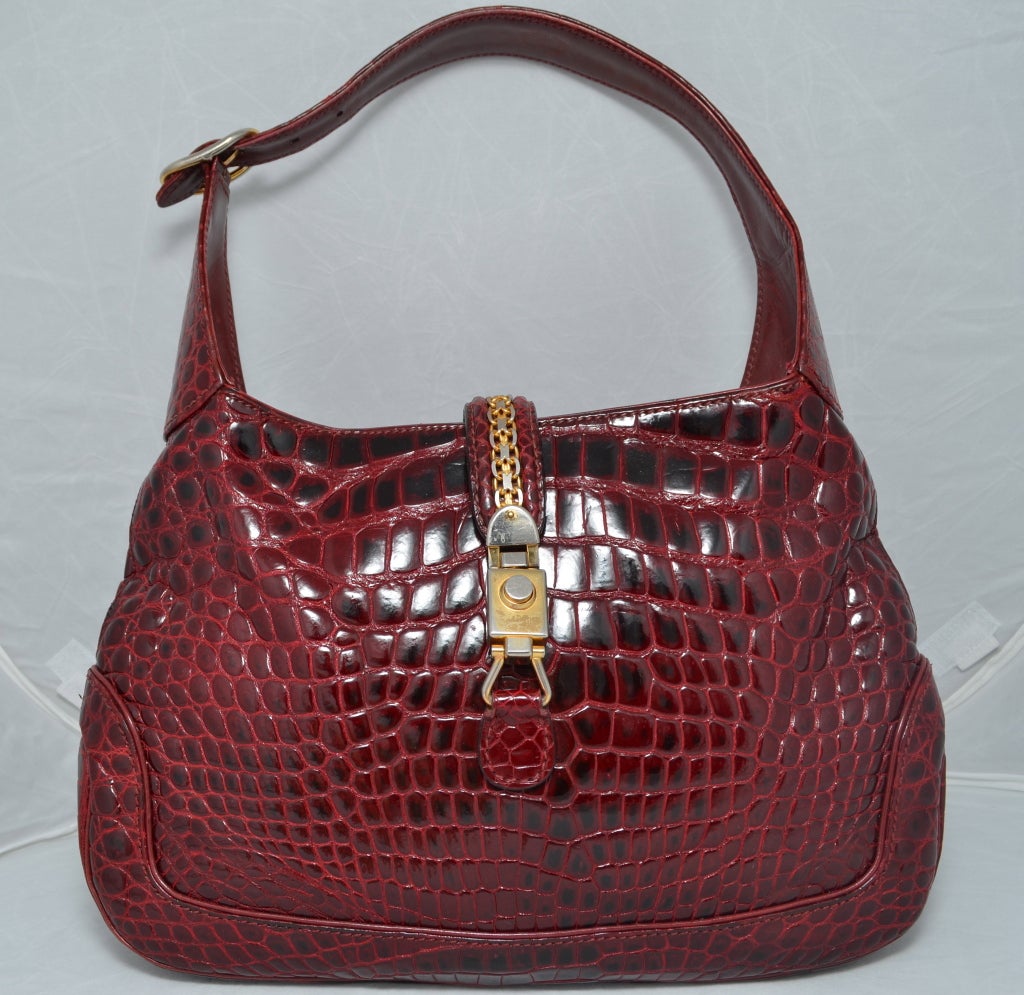 Gucci 1970's maroon crocodile Jackie O handbag with gold hardware. Push button clasp closure. Chain detail on closure strap. Inside pocket with Gucci charm attached. Gold cursive Gucci Made in Italy has been covered up in restoration so it is no