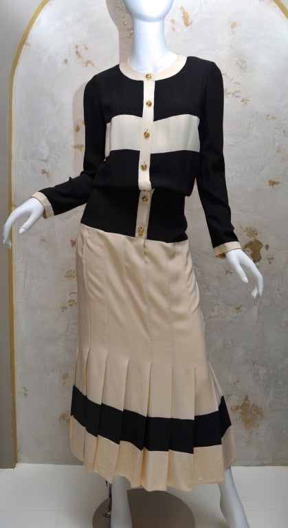 Chanel vintage 1984 silk dress with bold black and white stripes. Classic shirt dress with gold clover buttons. Dress gives the illusion of being a blouse and a skirt but it is one piece. Excellent quality of details such as grosgrain ribbon at