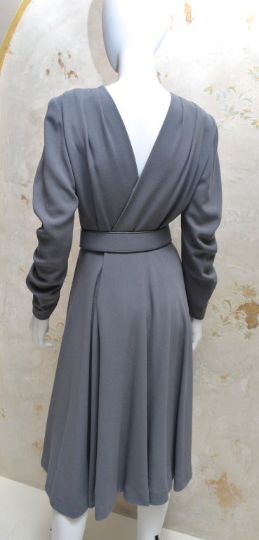 Galanos grey wool crepe wrap dress with back hook closure and exceptional pleated sleeves. Matching fabric belt or obi style wrap belt can be worn with this dress. Many high design details set this dress apart.  Unusual in that it closes in the back