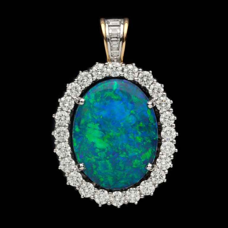 House of Giulians Opal and Diamond Pendant features 1 Oval Cut Black Opal with even blue & green fire for approximately 25cts set with 29 Mixed Cut diamonds for approximately 3.60cts.  Pendant is 28mm wide x 42mm long, including the bail, and weighs