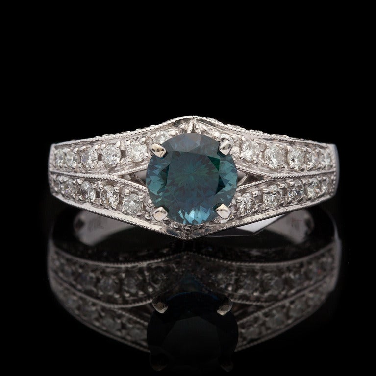 14Kt White Gold Ring features one Round Brilliant Cut Natural Dark Greenish Blue Sapphire for a total weight of 1.42cts accented by approximately 0.63cts of Round Brilliant Cut Diamonds.  The total weight of the ring is 5.1 grams and is a size 6.75.