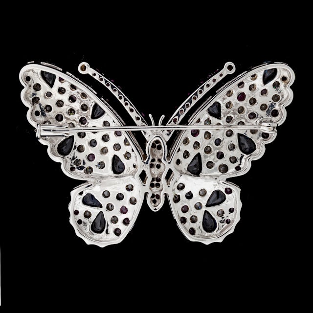 18Kt White Gold Butterfly Brooch with a total of approximately 5.25cts of Multi-Colored Sapphires and Rubies set with 61 Diamonds for a total approximate weight of 4.27cts. Brooch weighs 22.3 grams, and measures 38mm x 53mm.