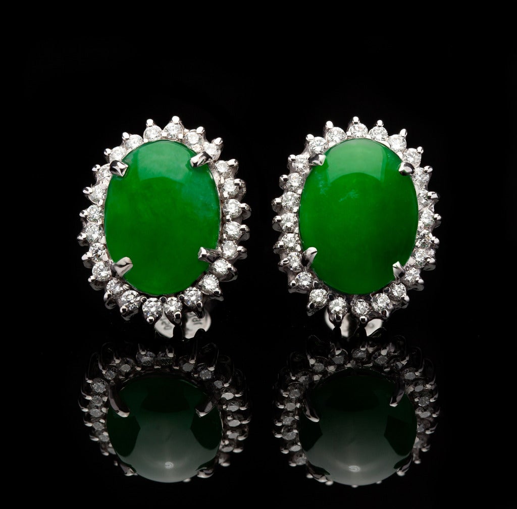 18Kt White Gold Oval Double Cabochon Cut Jade Earrings set with 48 Round Brilliant Cut Diamonds for approximately 0.80ct. The total weight of the earrings is 7.8 grams and they measure 15 x 18mm. Jade is natural with no indications of impregnation