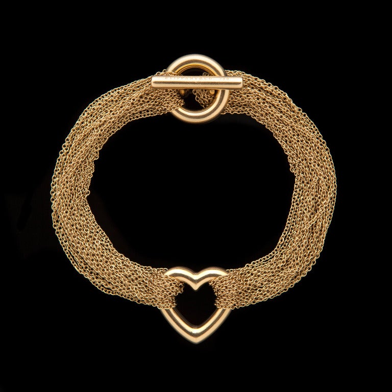 Tiffany & Co 18Kt Yellow Gold Mesh Heart Bracelet with a toggle clasp measures 16mm in width and has a 7″ bracelet.  The bracelet weighs 25.1 grams.