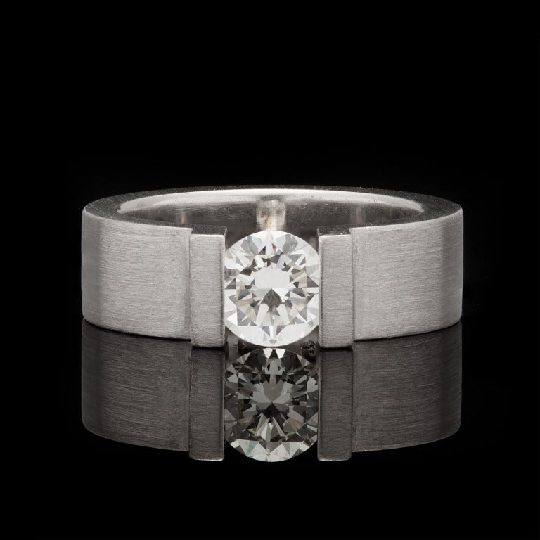Niessing Platinum & Diamond Solitaire band that has a Round Brilliant Cut Diamond, set in a tension mounting, for an approximate weight of 0.87cts with a J/K color and VS clarity. Ring has a brushed, matte finish 6mm in width, it weighs 15.9 grams,