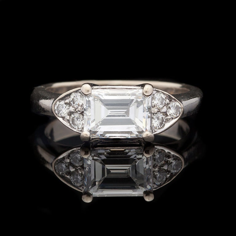 18Kt White Gold Diamond Ring has a 1.11ct Emerald Cut Diamond with F color and VVS2 clarity set with an additional 6 Round Brilliant Cut Diamonds for approximately 0.12cts. Ring weighs 4.6 grams, a size 5.5, and GIA report # 14714099 is included.