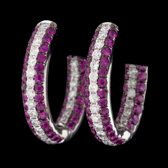 18Kt White Gold hoop style earrings with approximately 2.5cts of Round Brilliant Cut Rubies and 1.0cts of Round Brilliant Cut Diamonds.  The earrings measure 5mm wide, 23mm in diameter, and weigh 8.5 grams.