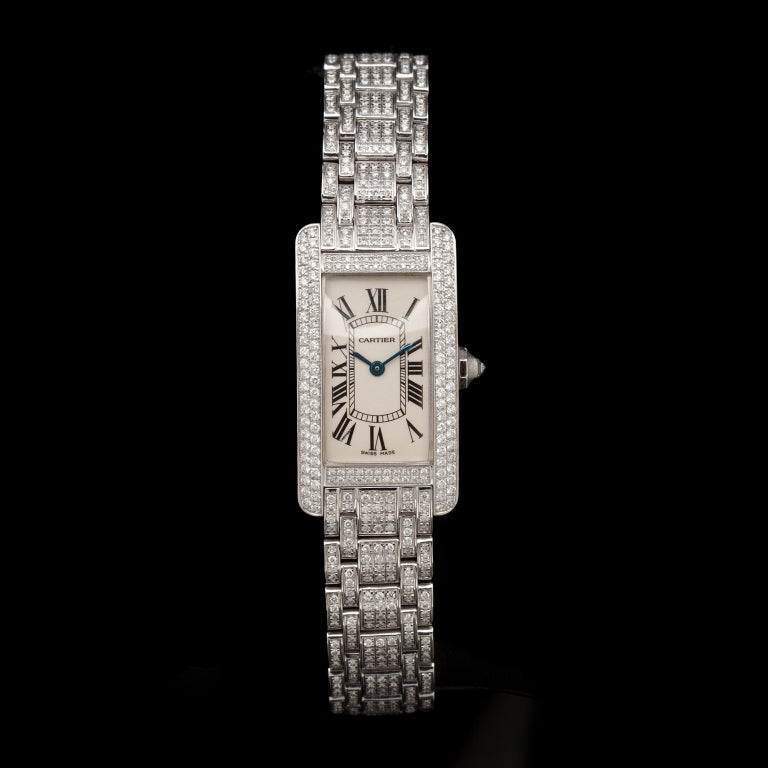 Cartier 18k white gold Tank Americaine wristwatch with fully pave-set diamond case and bracelet. Weighs 81.9 grams. Watch has a quartz movement with a 19 x 35mm case and white dial with black Roman numerals. It has a 7