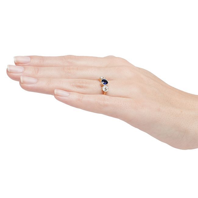 Sunny Point is a pleasant Edwardian era three stone engagement ring made from platinum and 18k yellow gold centering a round natural sapphire gauged at approximately 0.68ct. This sparkling sapphire sits in a delicate platinum bezel accented with