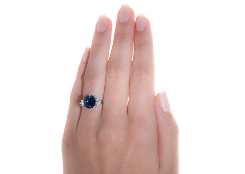 Wedegfield showcases a bright sapphire in this traditional three-stone ring made from platinum. This streamlined ring features a deep blue GIA certified oval natural sapphire stating Sri Lankan origin. It has been estimated to weigh 3.92 carats and